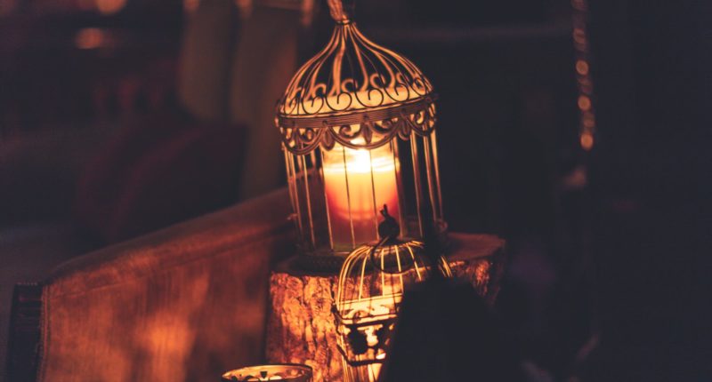 photo of brown metal cage with lighted candle